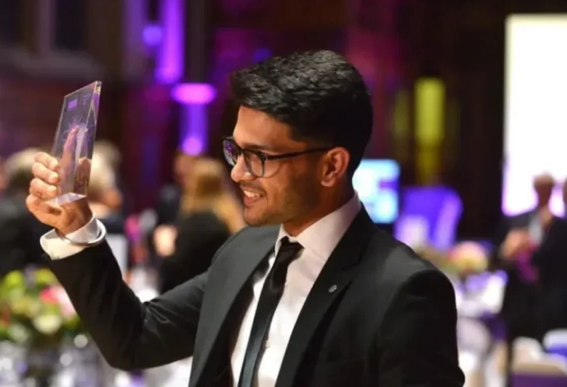 Sid Sethi, Specscart’s founder, dressed in a suit and tie, holding up the Venture Further Award trophy at a formal event in 2018. The background shows an elegant venue with guests, capturing a milestone moment for the company.